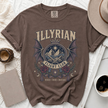 Brown t-shirt with a circular graphic featuring mountains, wings, roses, and the text "ILLYRIAN FLIGHT CLUB".