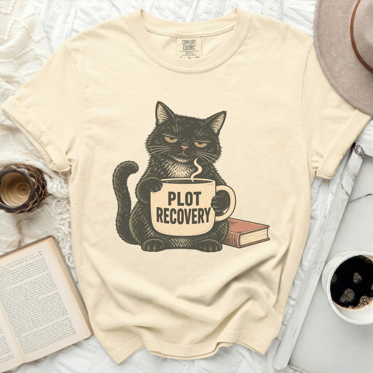 Black cat with grumpy expression holding mug that says "PLOT RECOVERY".