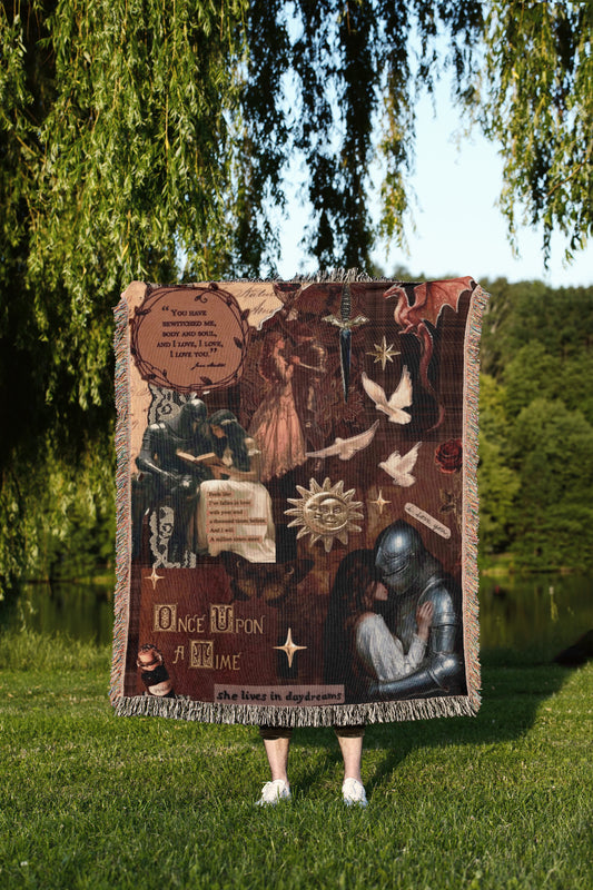a person standing in a grassy area, holding a large, colorful blanket that appears to be a collage of various images and text.