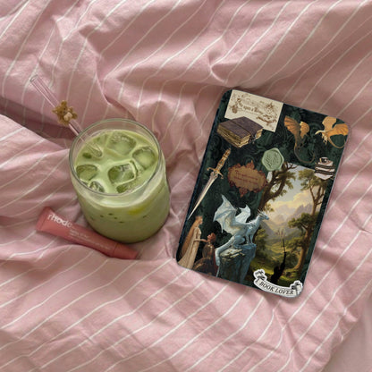 A matcha latte, lip balm, and fantasy-themed "Book Lover" sticker on pink striped fabric.