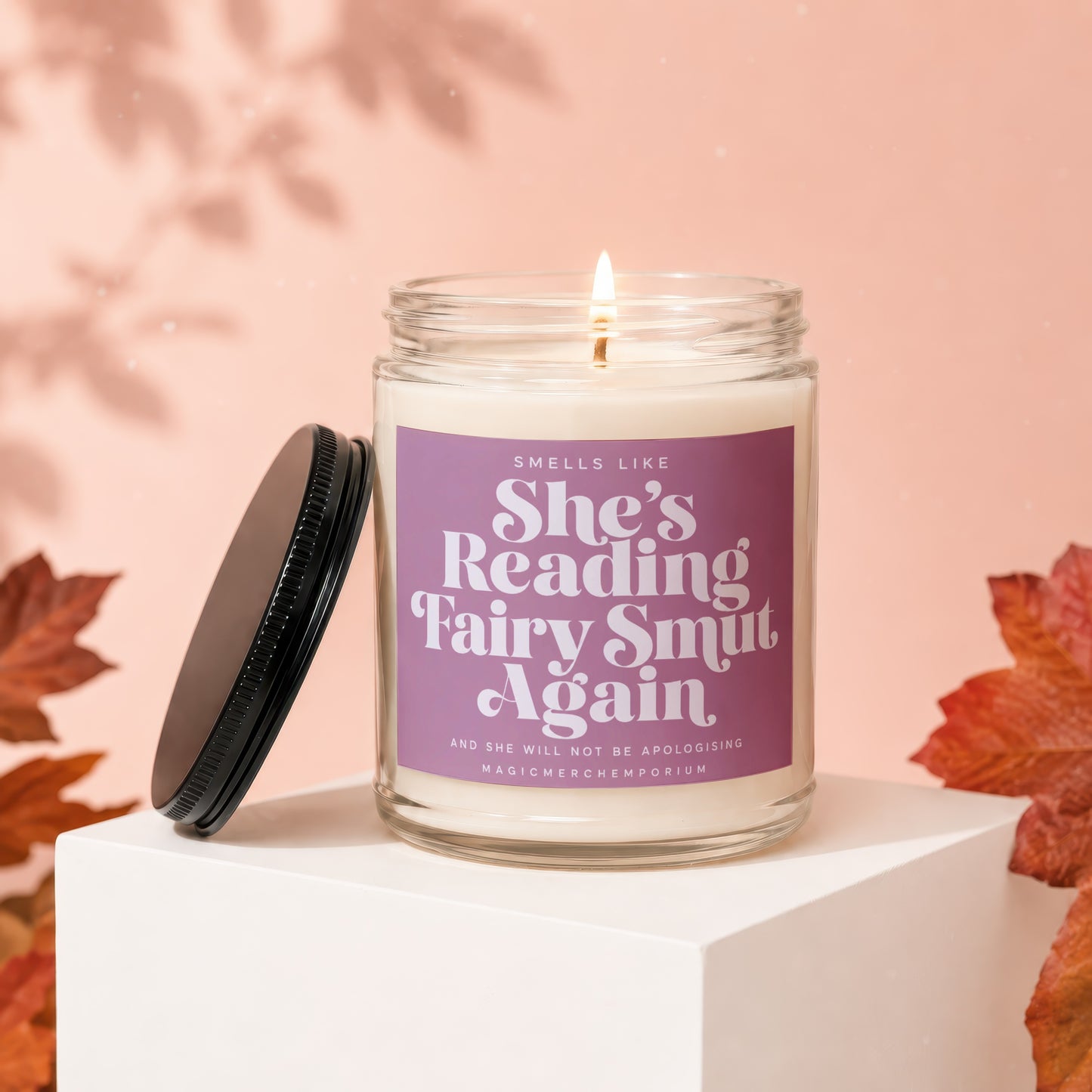 Candle with purple label reading "Smells Like She's Reading Fairy Smut Again".