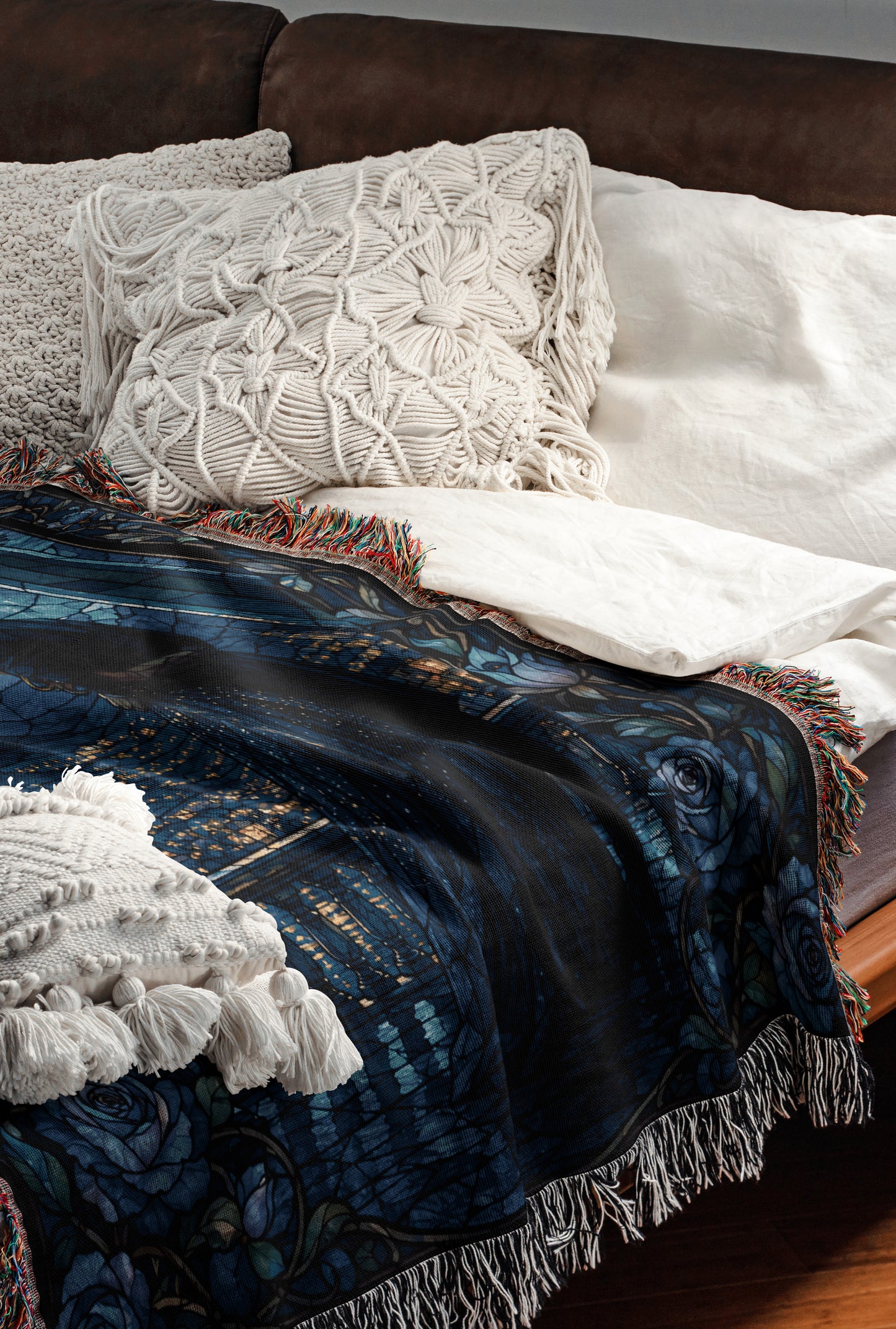 a cozy and inviting bedroom scene, featuring a bed with a blue and black patterned blanket, white pillows, and a brown leather couch.