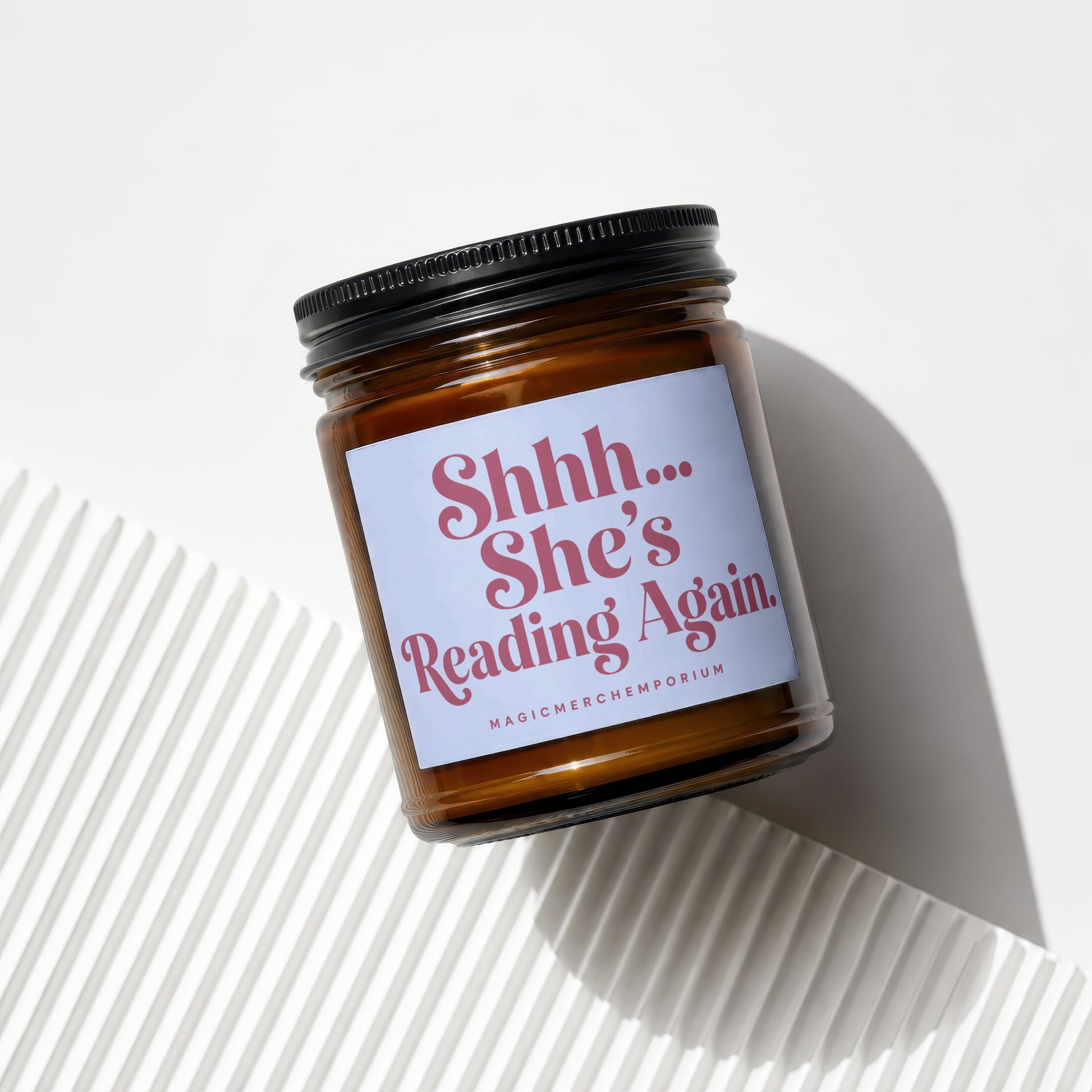 Amber jar candle with "Shhh... She's Reading Again." text and brand name.