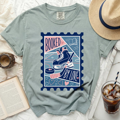 T-shirt graphic with hockey skates, puck, book, and "Booked by Love" text.