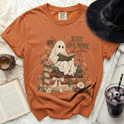 Orange t-shirt with a ghost reading a book on stacked books.
