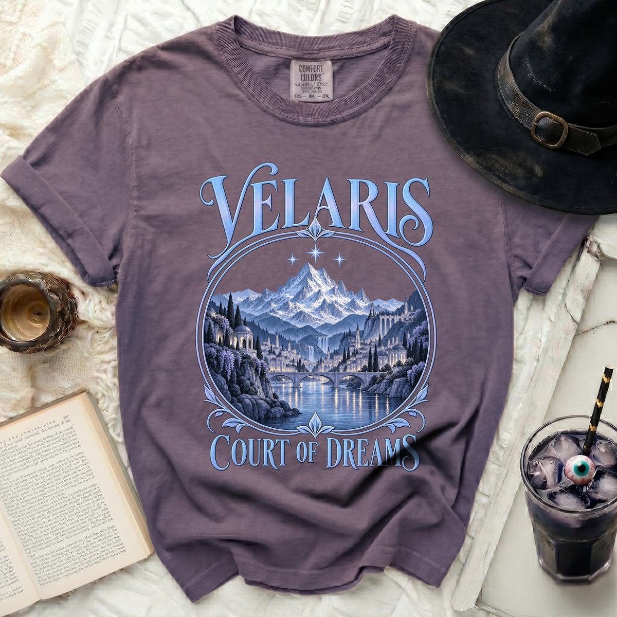 Purple t-shirt with "Velaris Court of Dreams" text and fantasy landscape design.