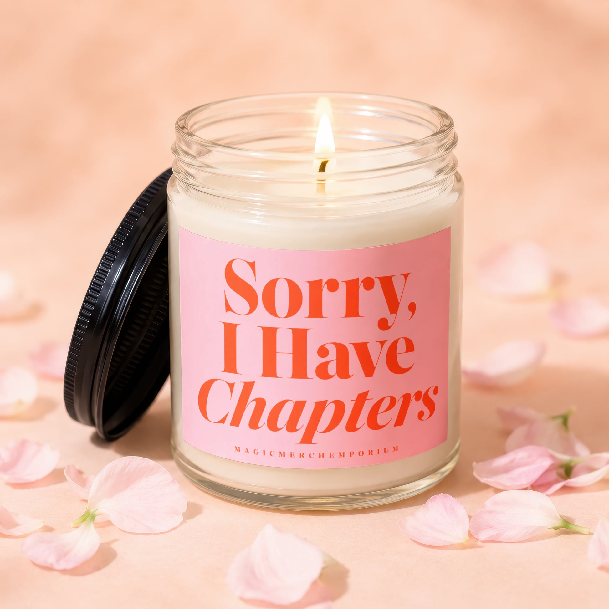 Glass jar candle with pink label reading "Sorry, I Have Chapters".