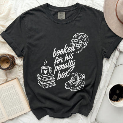 T-shirt with "booked for his penalty box" graphic featuring hockey gear and books.
