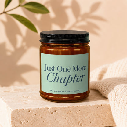 Amber jar candle with light blue label reading "Just One More Chapter".