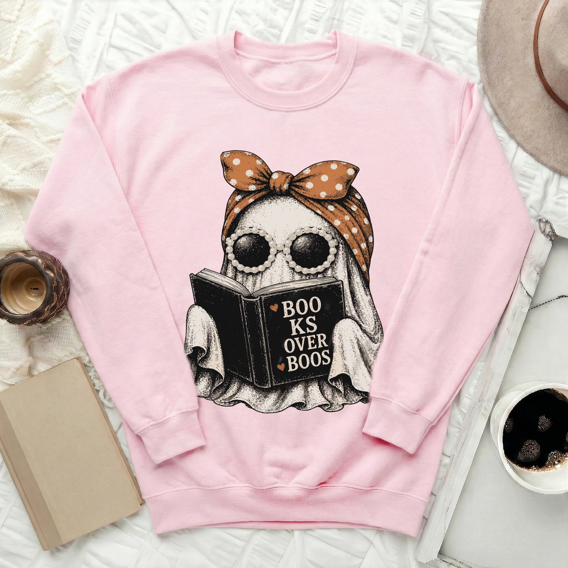 Pink sweatshirt with a ghost reading a book that says "Books over Boos."