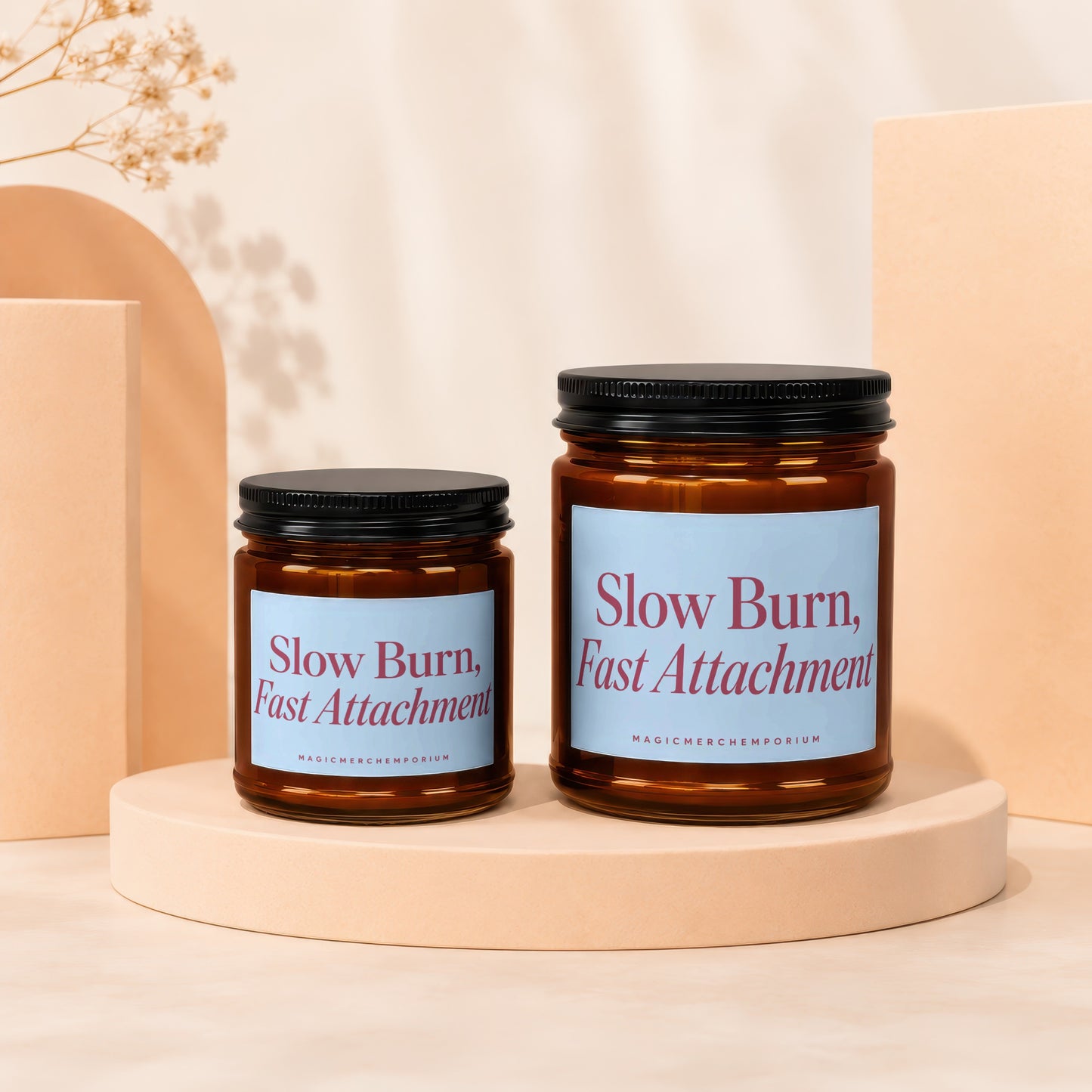 Two amber glass candles with black lids, reading "Slow Burn, Fast Attachment."