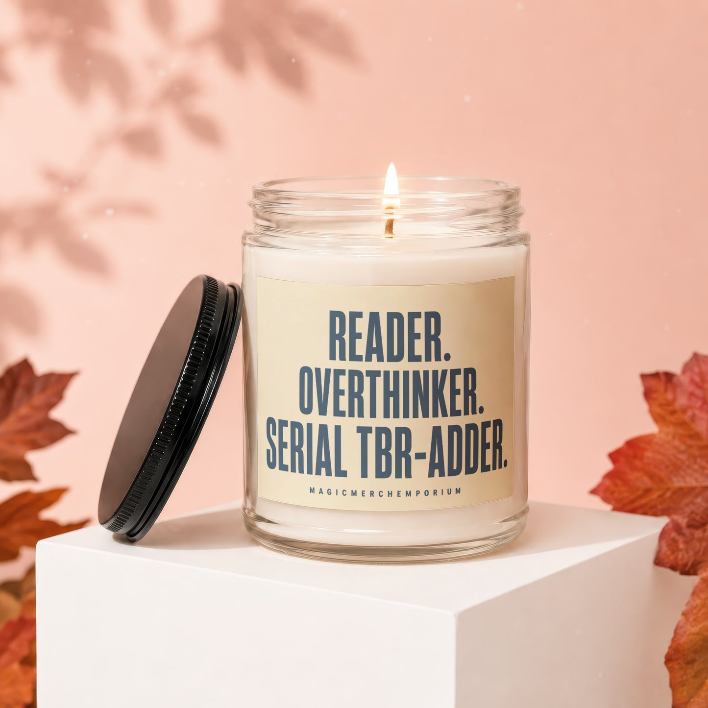 Lit candle in a glass jar with a cream label reading "READER. OVERTHINKER. SERIAL TBR-ADDER."