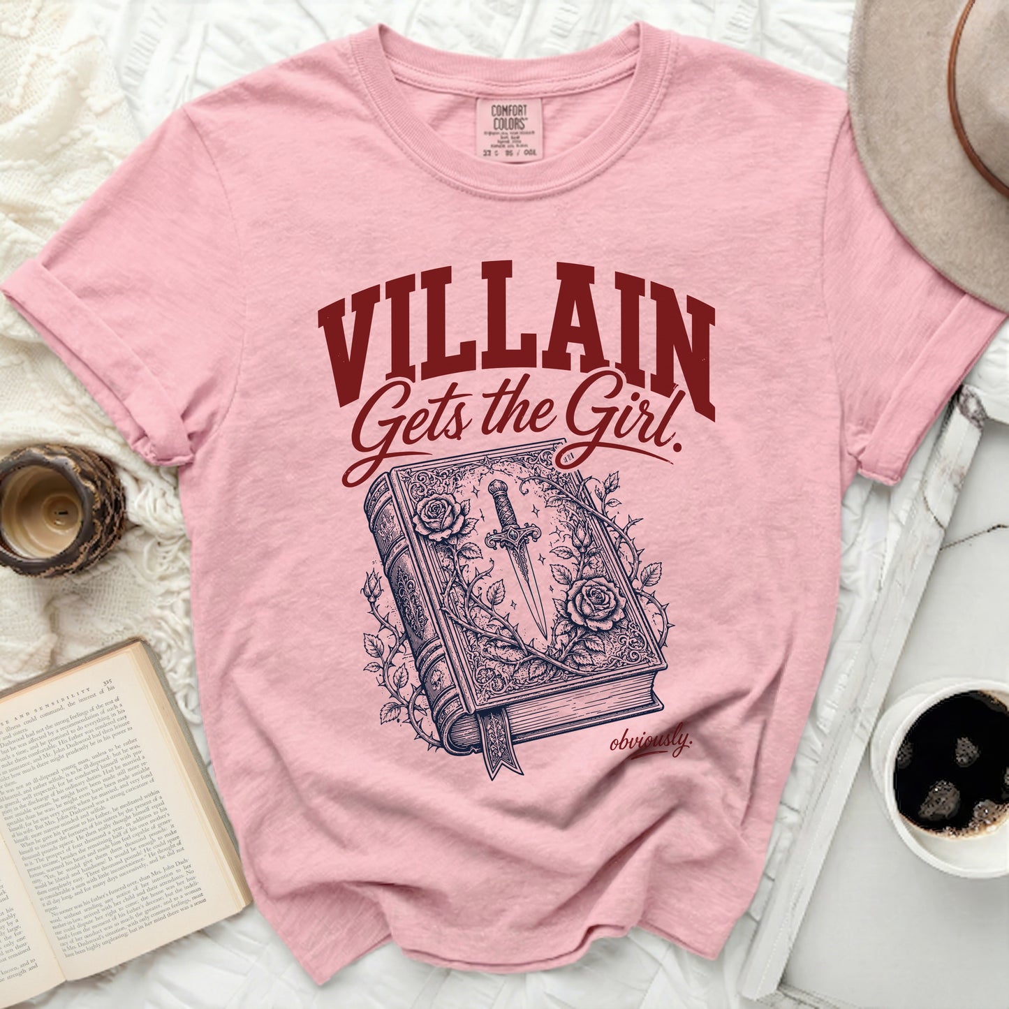 Pink t-shirt with "VILLAIN Gets the Girl" and a book with sword illustration.