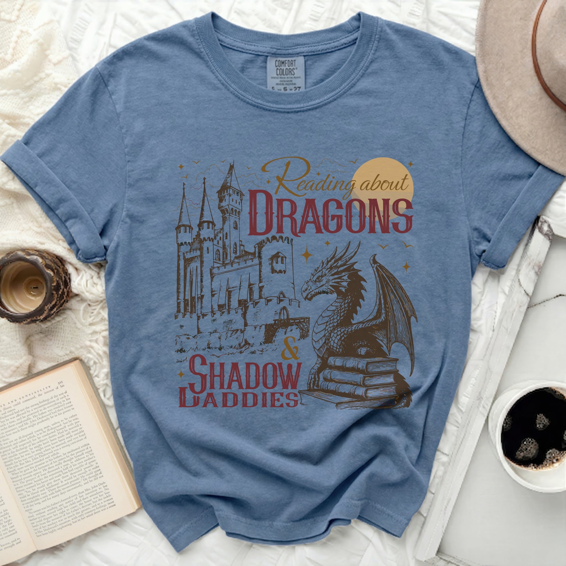 Blue t-shirt with "Reading about DRAGONS & SHADOW DADDIES" graphic.