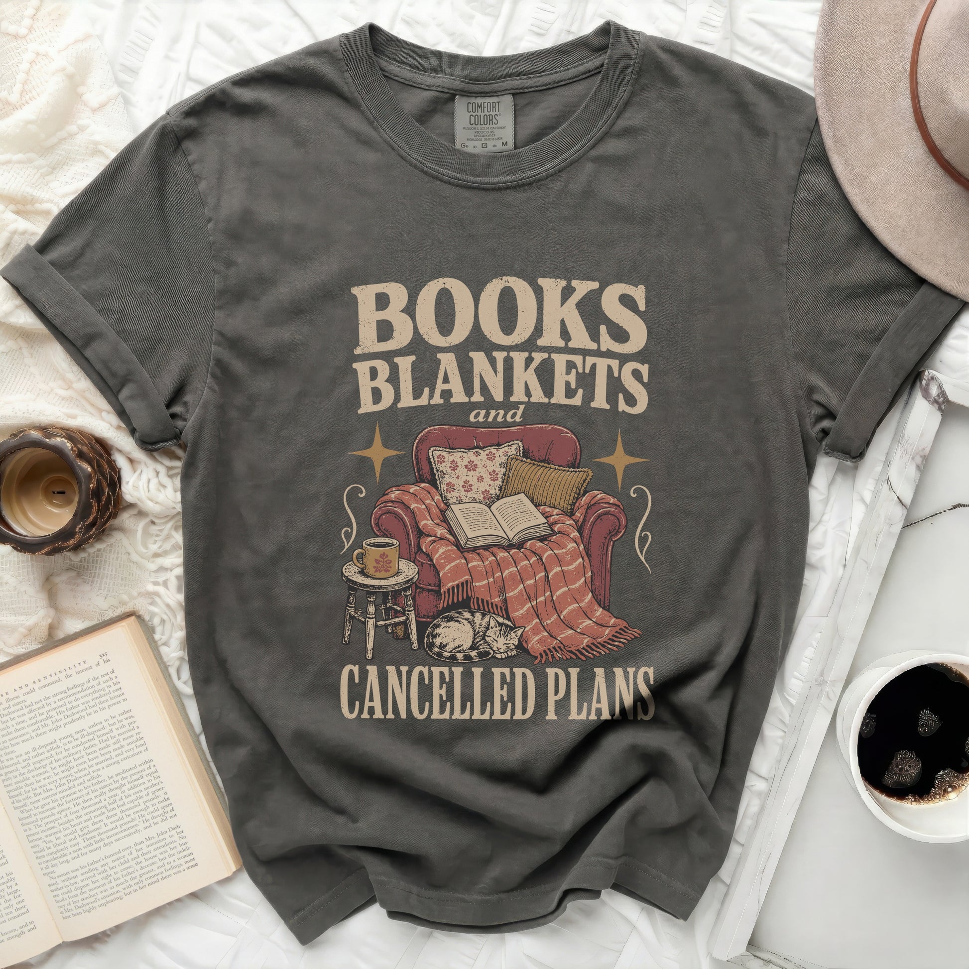 Gray t-shirt with "BOOKS BLANKETS and CANCELLED PLANS" text and illustration.