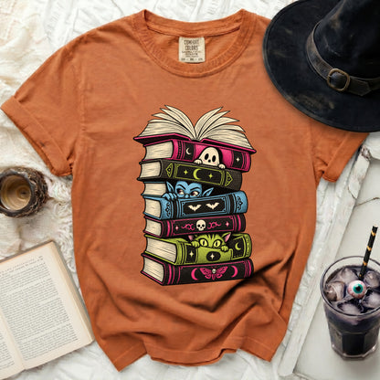 Orange t-shirt with stacked Halloween-themed books featuring a ghost, vampire, cat, and moth.