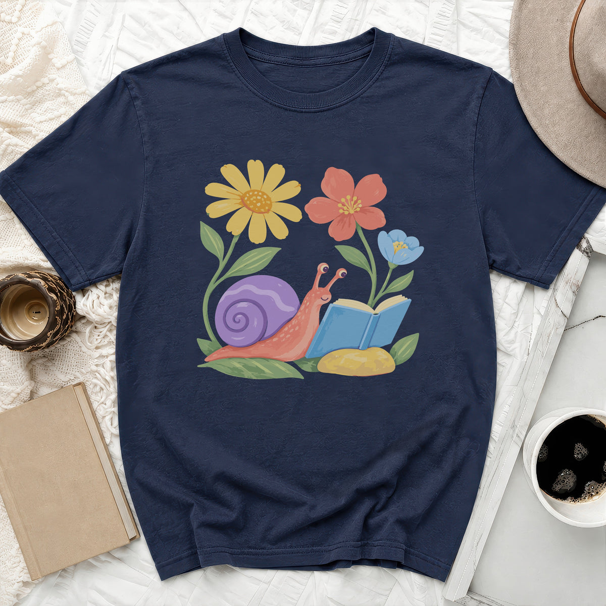 Navy t-shirt with illustration of a snail reading a book surrounded by flowers.