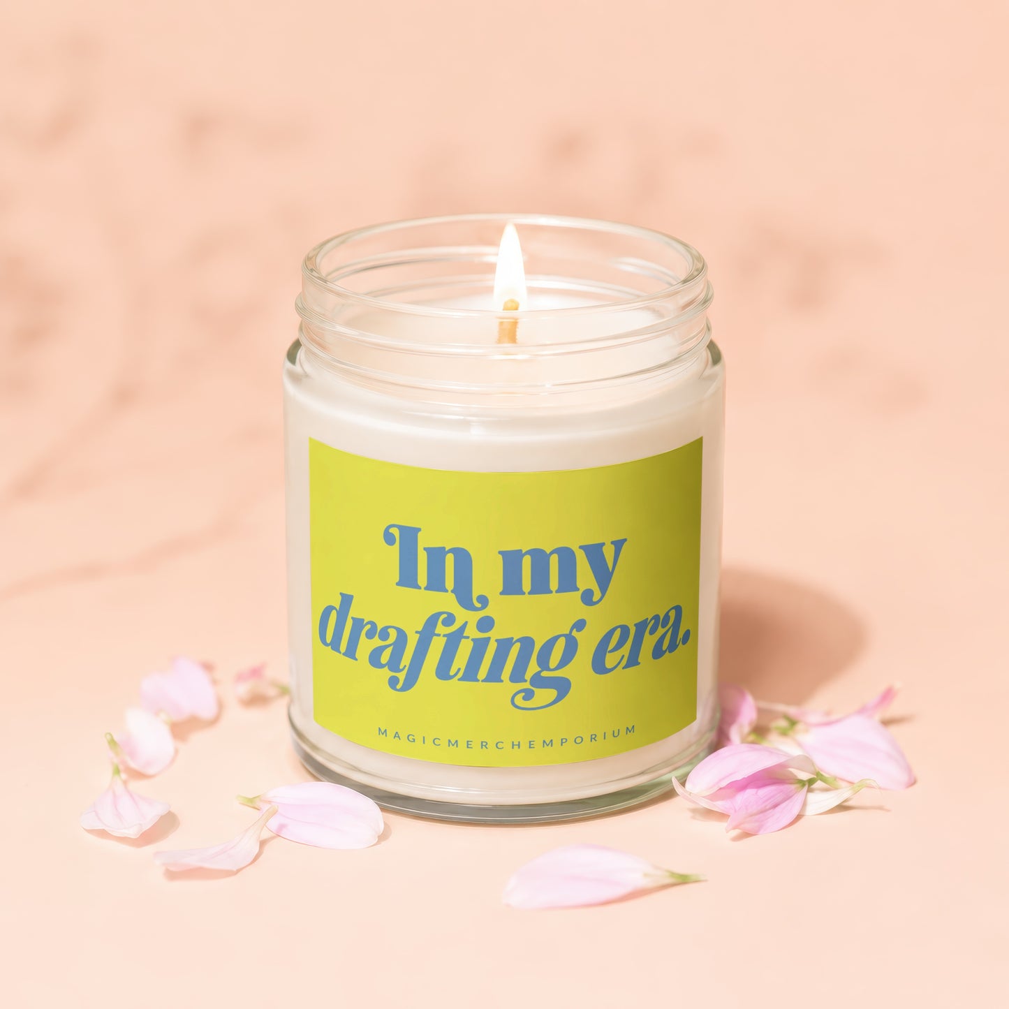 Candle with lit wick and green label reading "In my drafting era"