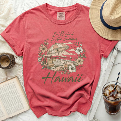 Coral t-shirt with "I'm Booked for the Summer Hawaii" floral graphic.