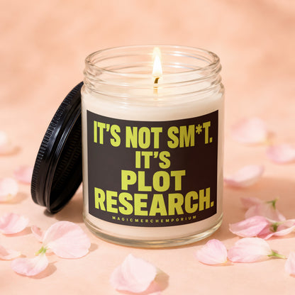 Glass candle with lit wick and black lid, reads "it's not sm*t. it's plot research."
