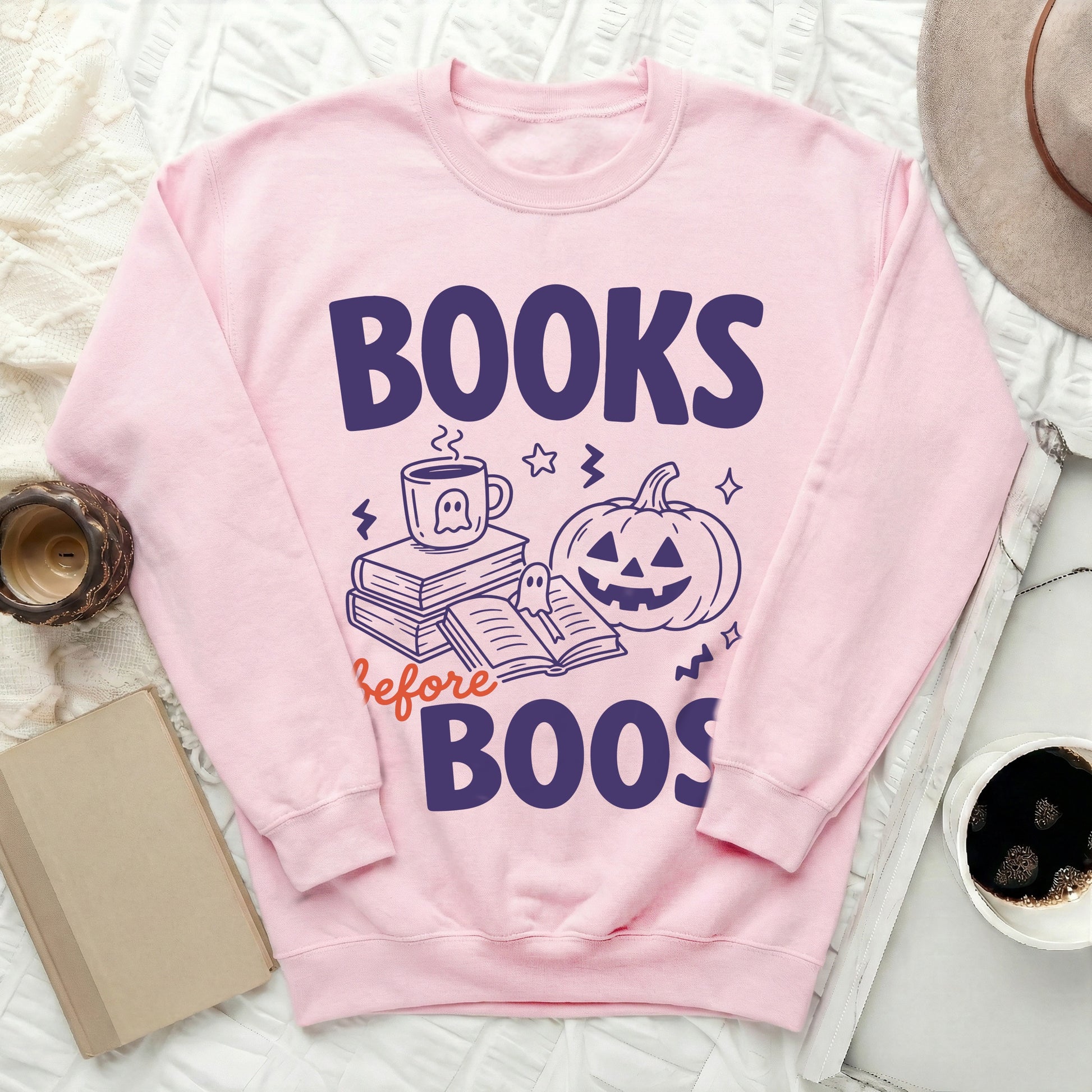 Pink sweatshirt with "Books Before Boos" graphic featuring books, a mug, and a pumpkin.