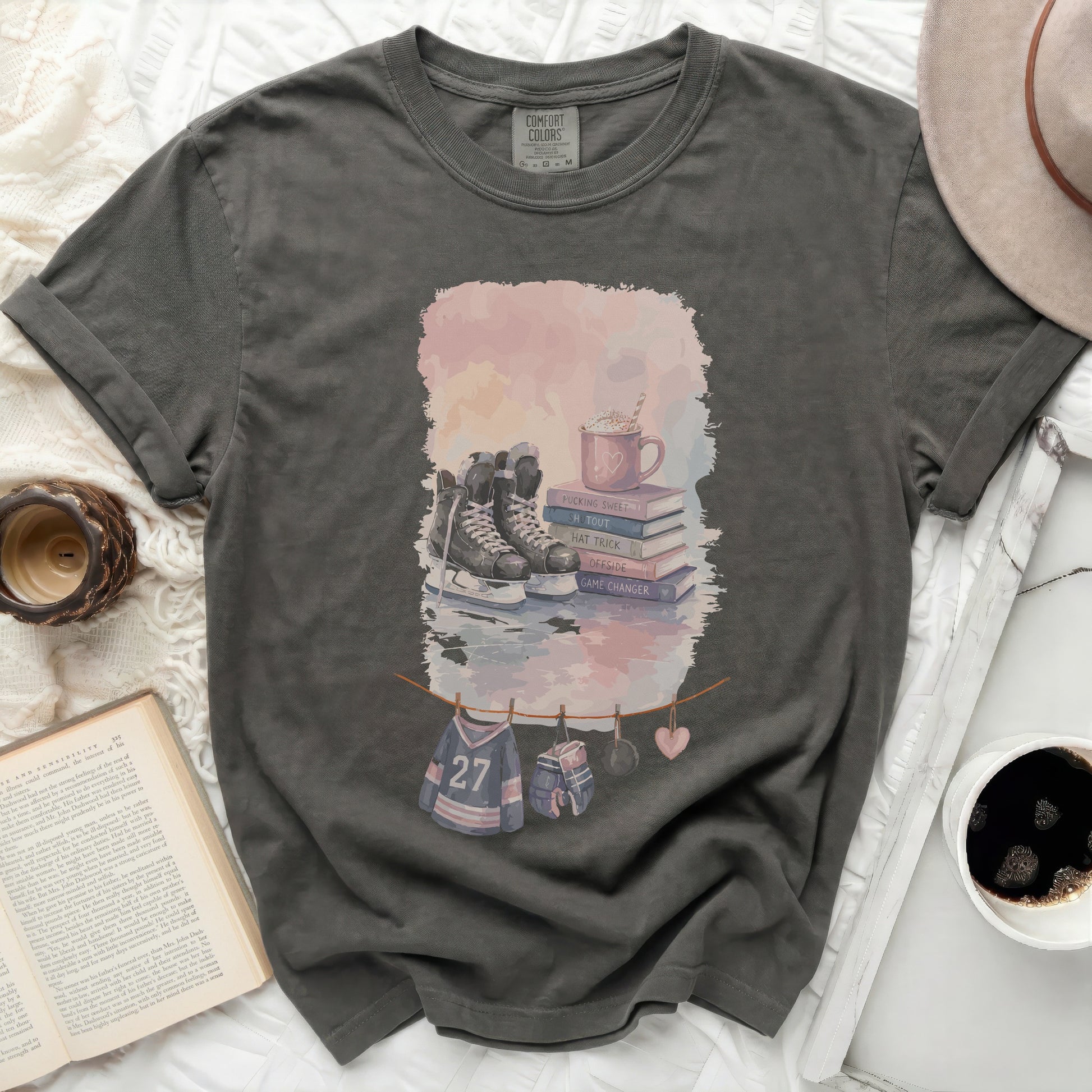 T-shirt with watercolor graphic of ice skates, hockey puck, hot chocolate, and jerseys.