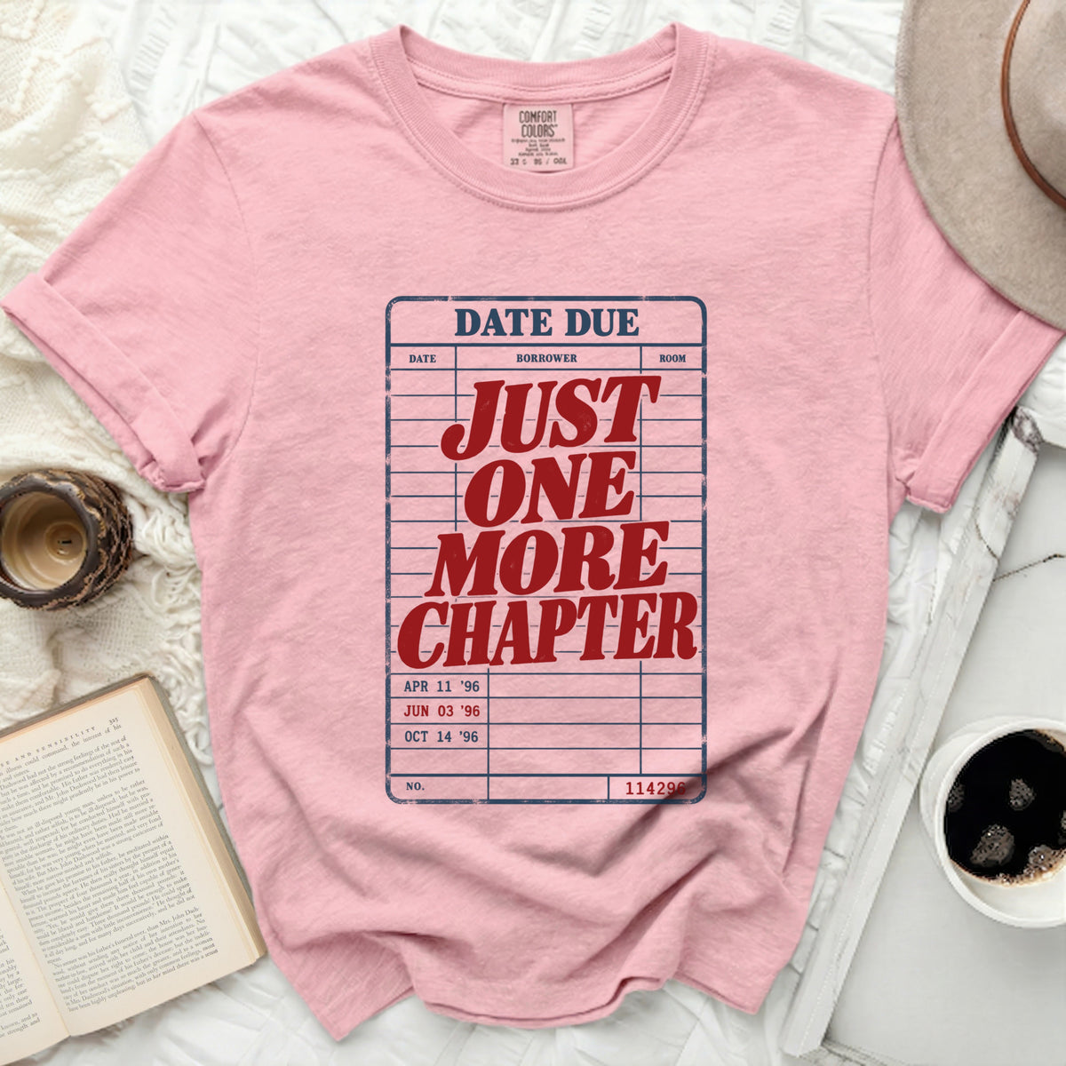 Pink t-shirt with "JUST ONE MORE CHAPTER" library card graphic.