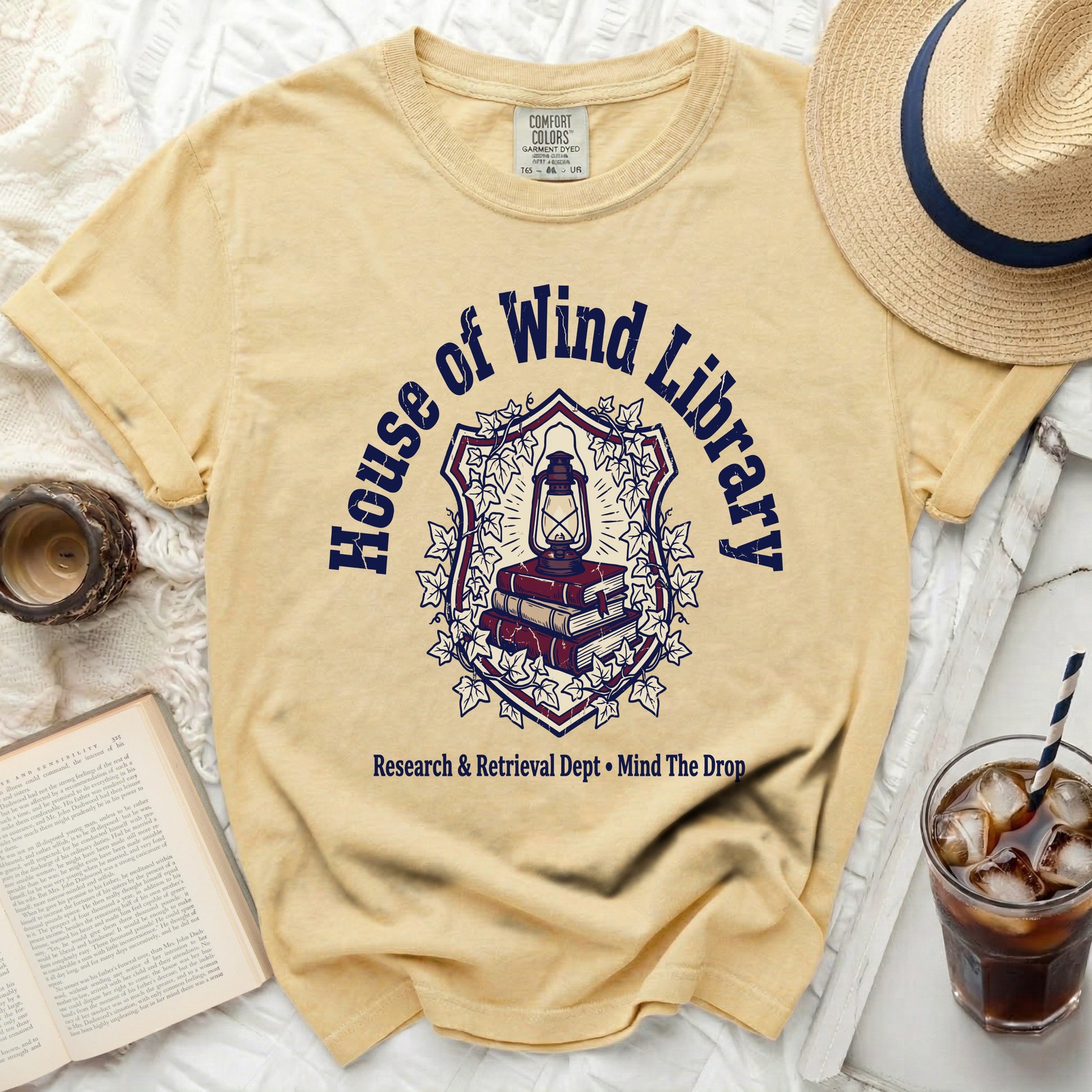 Yellow Comfort Colors t-shirt with "House of Wind Library" graphic.