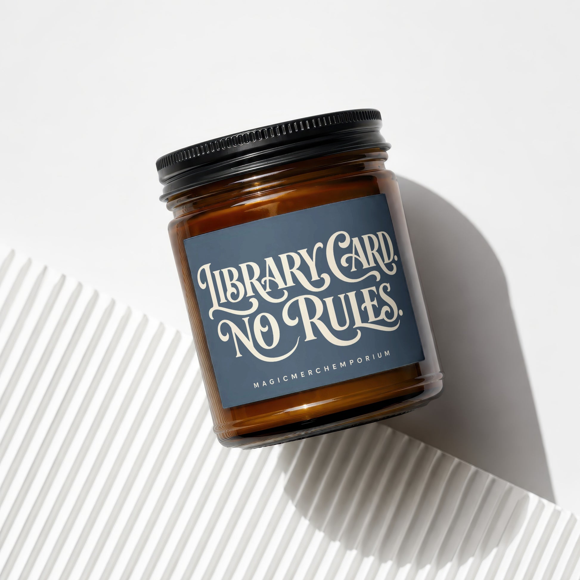 Amber candle with black lid and "Library Card, No Rules" label.