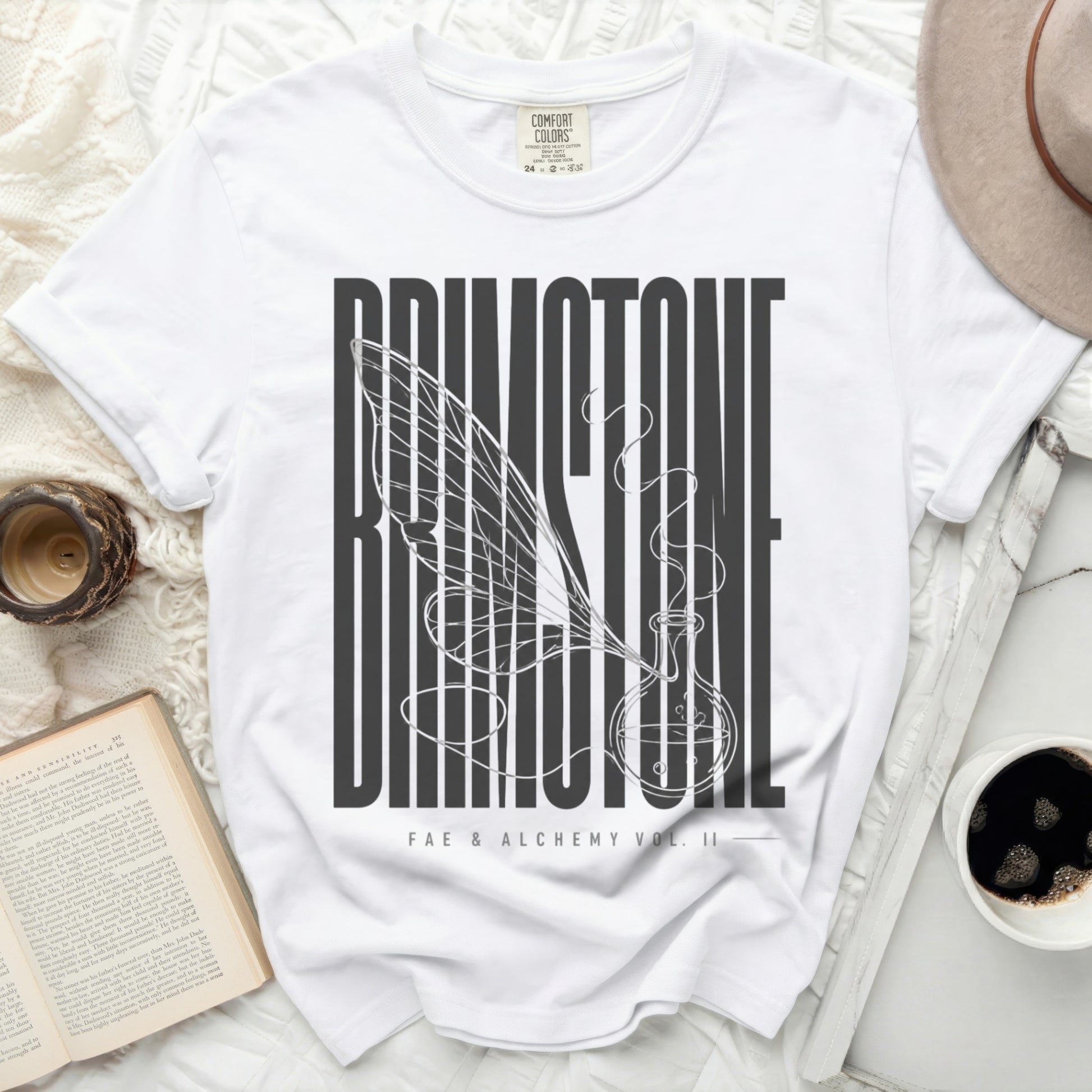 White t-shirt with "Faerie & Alchemy Vol. II" text and winged potion bottle.