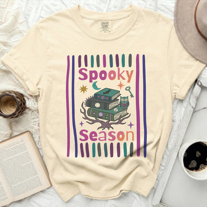 Cream t-shirt with a graphic of stacked books, owl, moon, and text "Spooky Season."