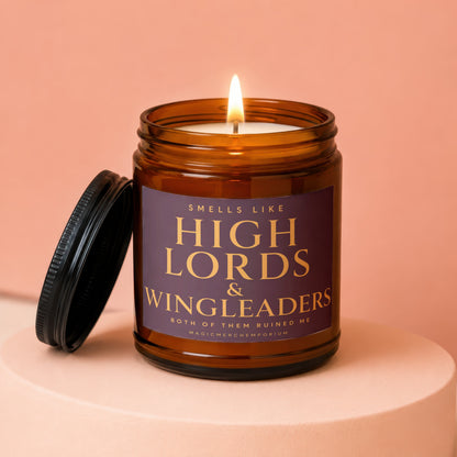 Amber candle with lit wick on a pedestal, labeled "Smells Like High Lords & Wingleaders".
