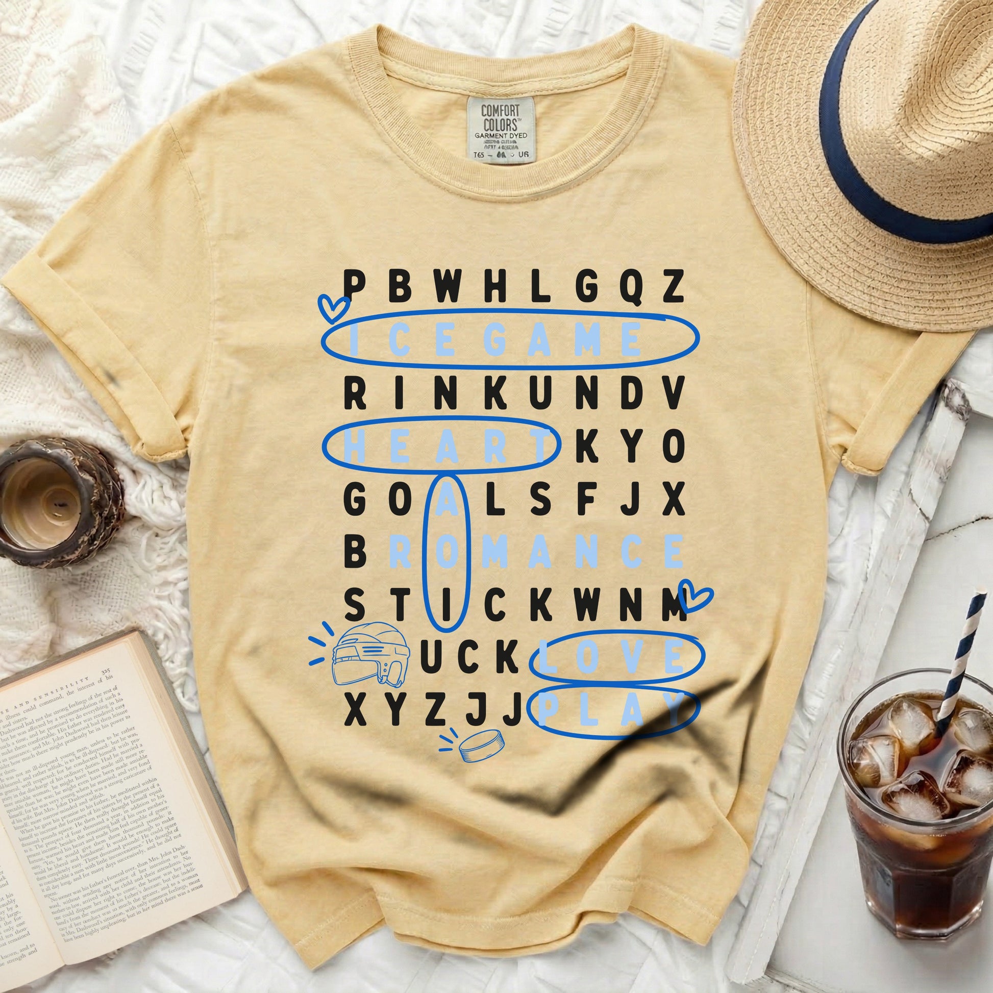 Yellow t-shirt with word game grid: "ice game" is central, hockey pucks.