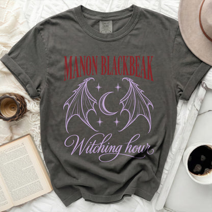 Dark grey t-shirt with "Manon Blackbeak" and "Witching Hour" text, bat wings, and moon design.
