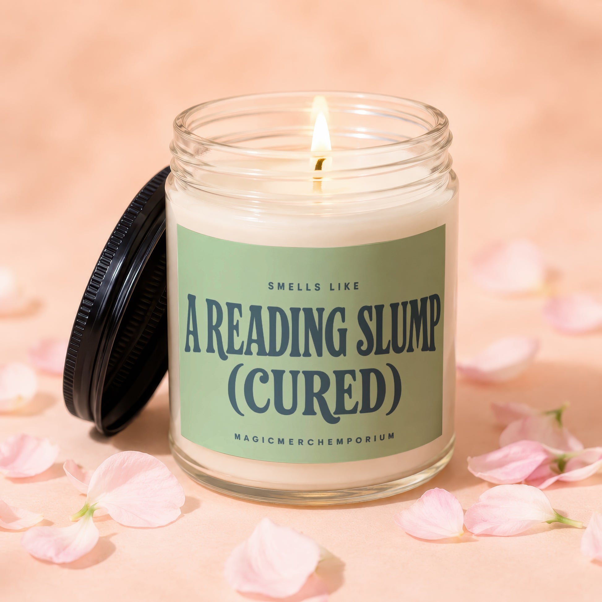 Lit candle in glass jar with green label reading "Smells like A Reading Slump (Cured)".