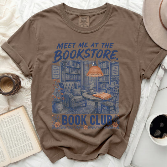T-shirt with "Meet me at the Bookstore" and cozy reading nook graphic.