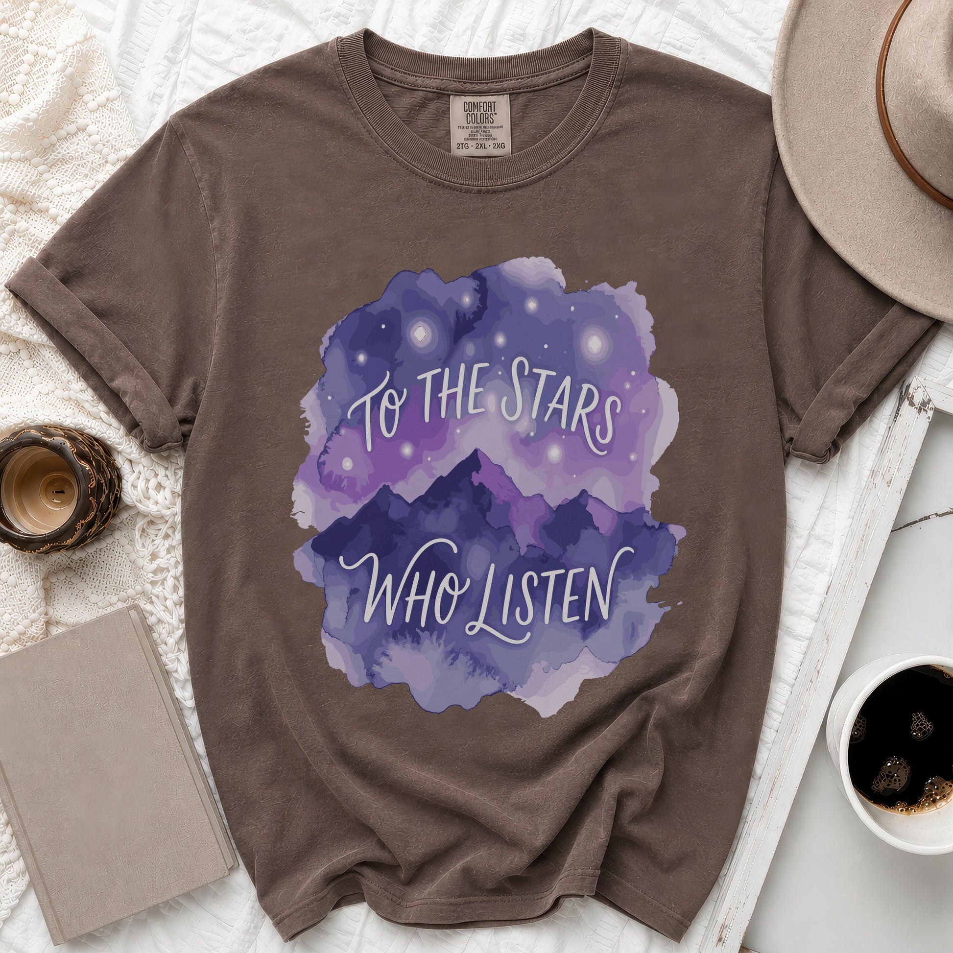 Brown t-shirt with watercolor mountains and stars graphic that reads "To The Stars Who Listen."