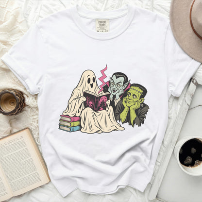 Ghost, vampire, and Frankenstein reading a book together on a white t-shirt.