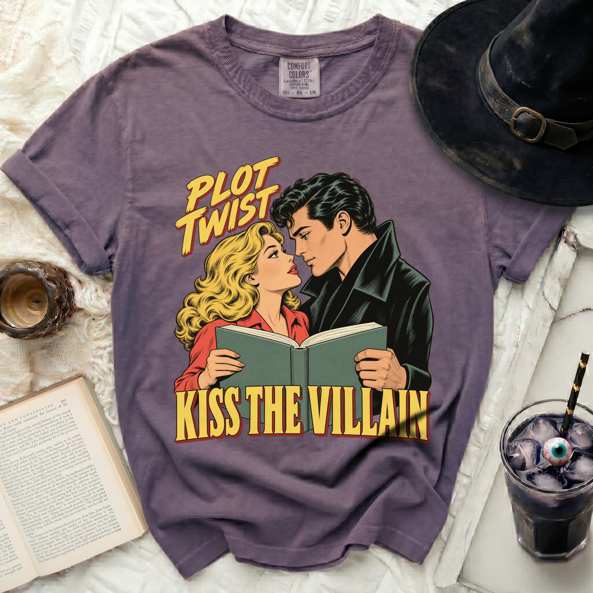 Purple t-shirt with comic style art of couple reading book and text "PLOT TWIST KISS THE VILLAIN".