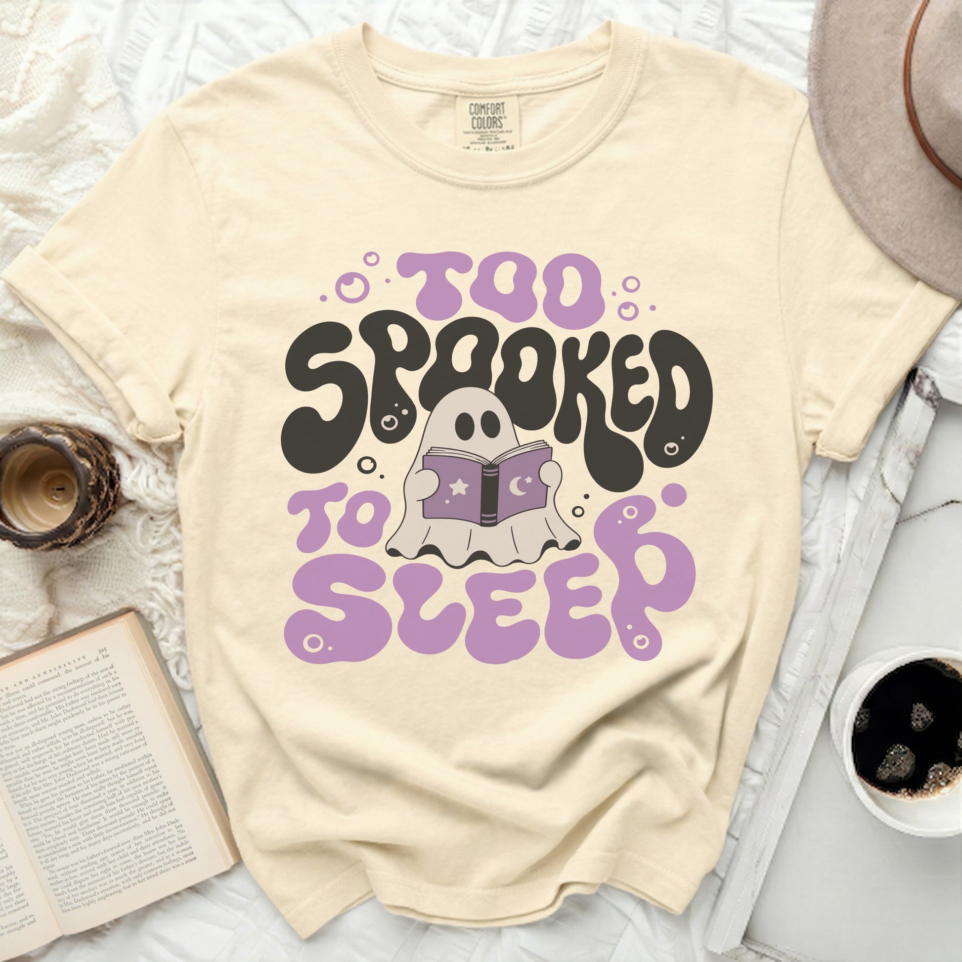 Cream t-shirt with "Too Spooked to Sleep" graphic and a ghost reading a book.