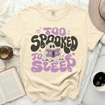 Cream t-shirt with "Too Spooked to Sleep" graphic and a ghost reading a book.