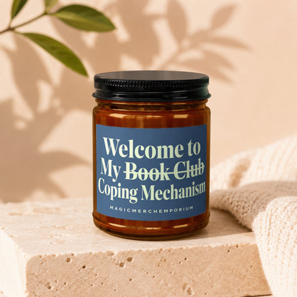 Amber jar candle with a blue label reading "Welcome to My Book Club Coping Mechanism"