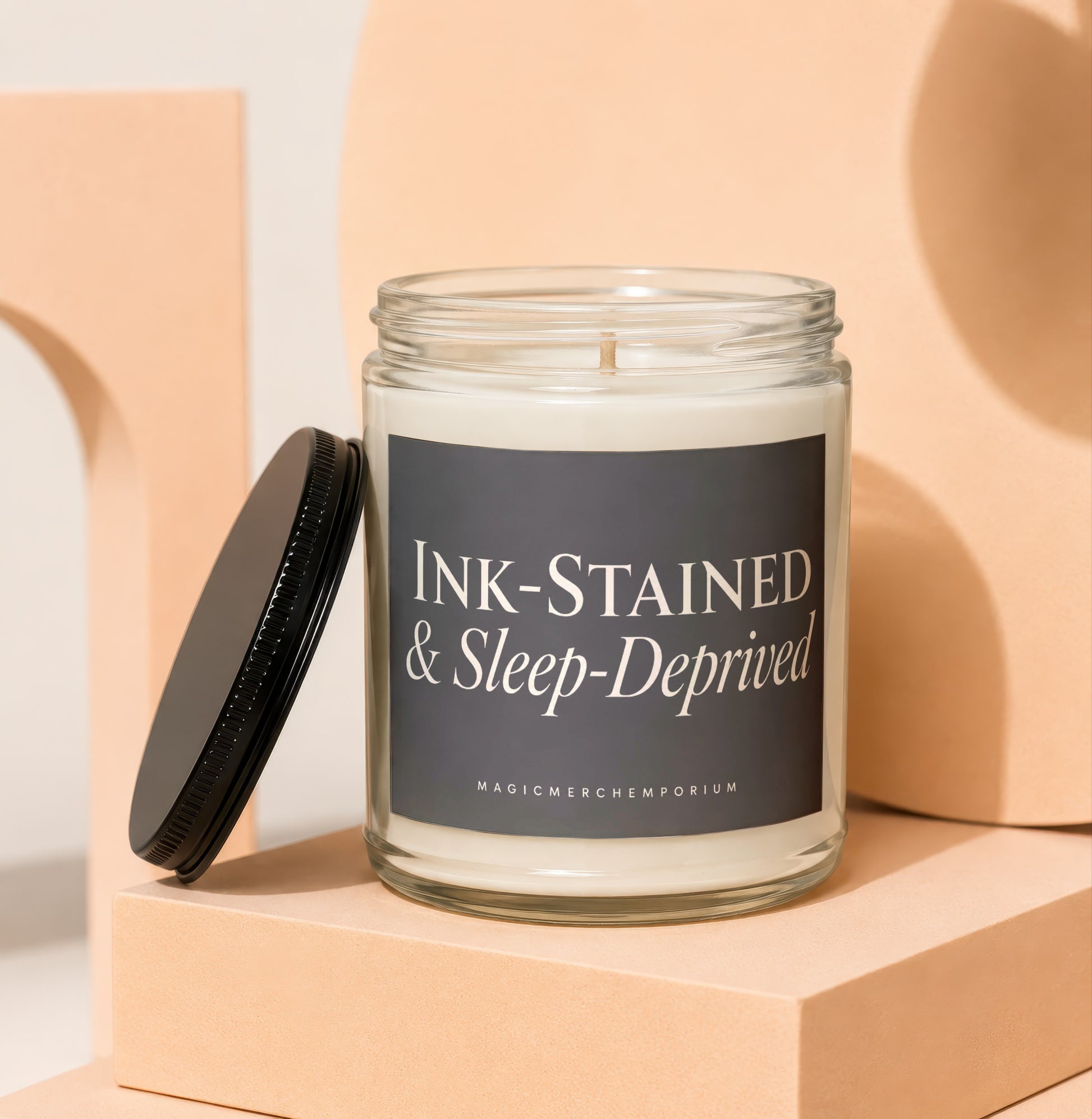 Glass jar candle with label reading "Ink-Stained & Sleep-Deprived".