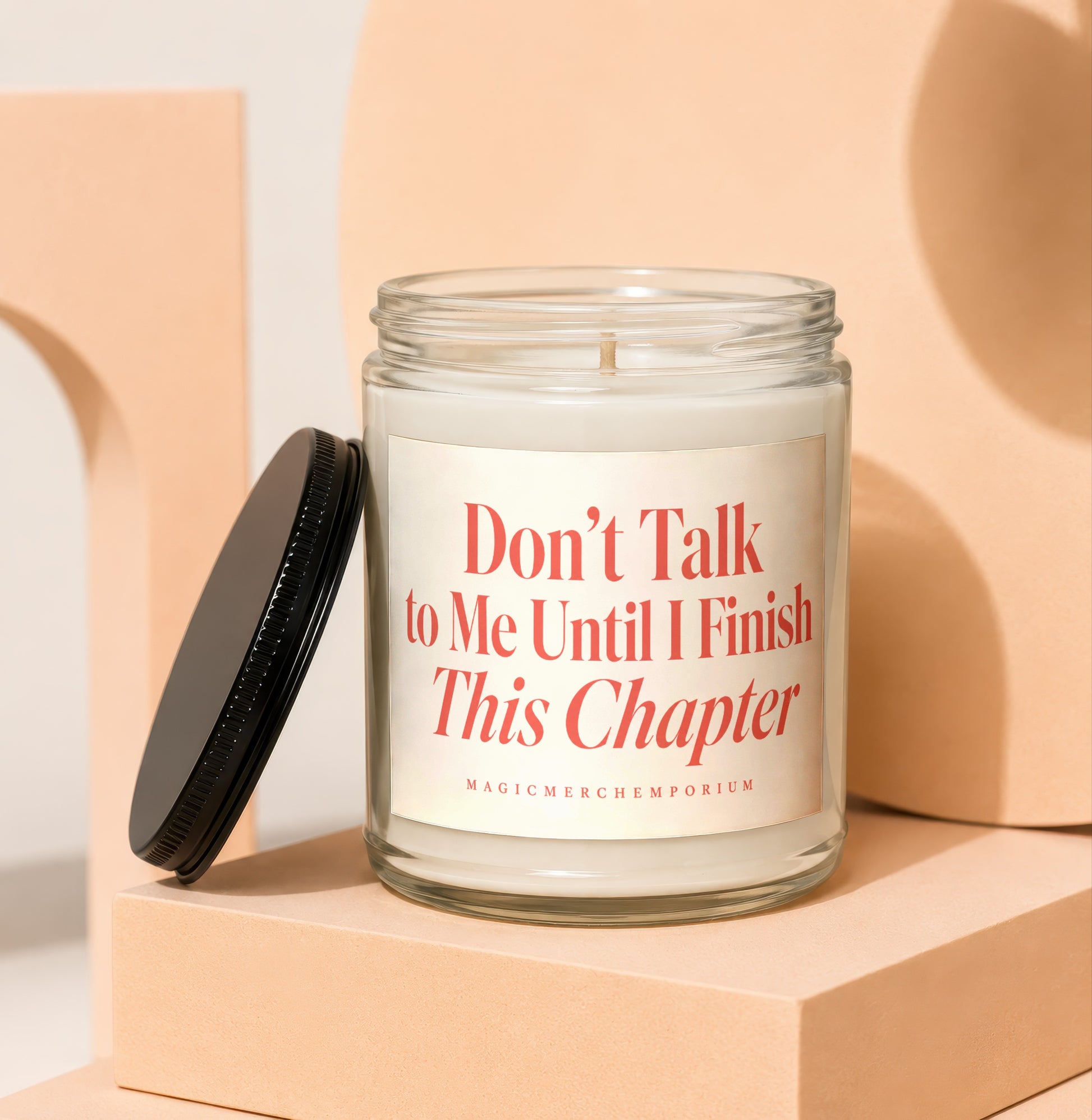 Glass candle with black lid nearby, label reads "Don't Talk to Me Until I Finish This Chapter."