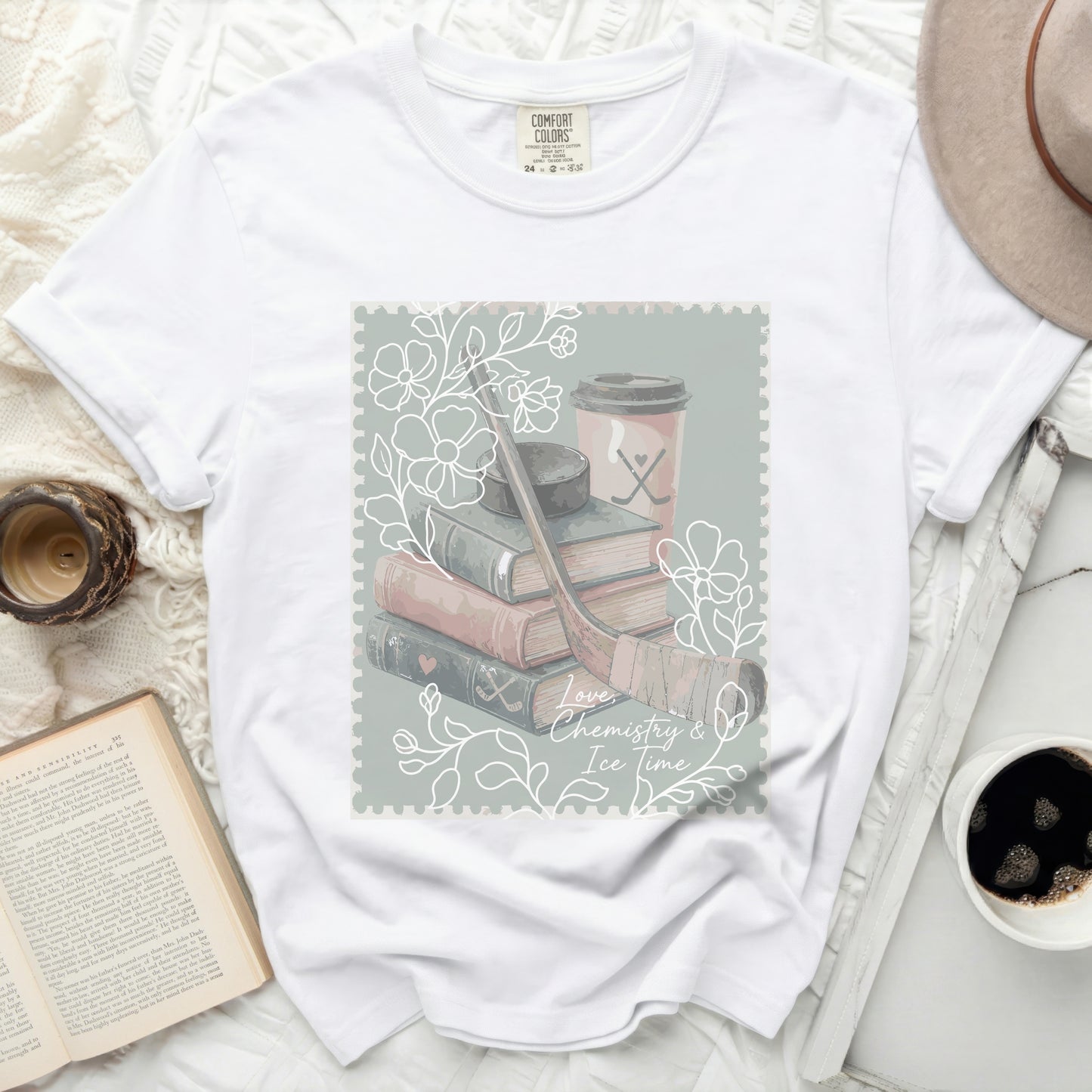 White t-shirt with a stamp graphic featuring books, hockey gear, and coffee.