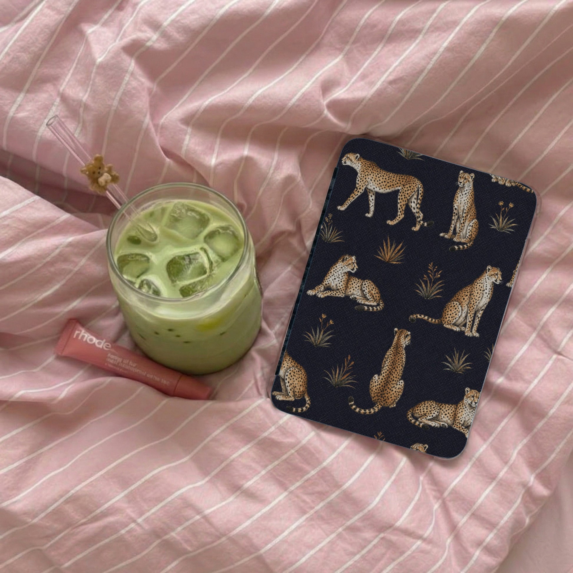 Dark blue case with a leopard print pattern on pink striped bedding.