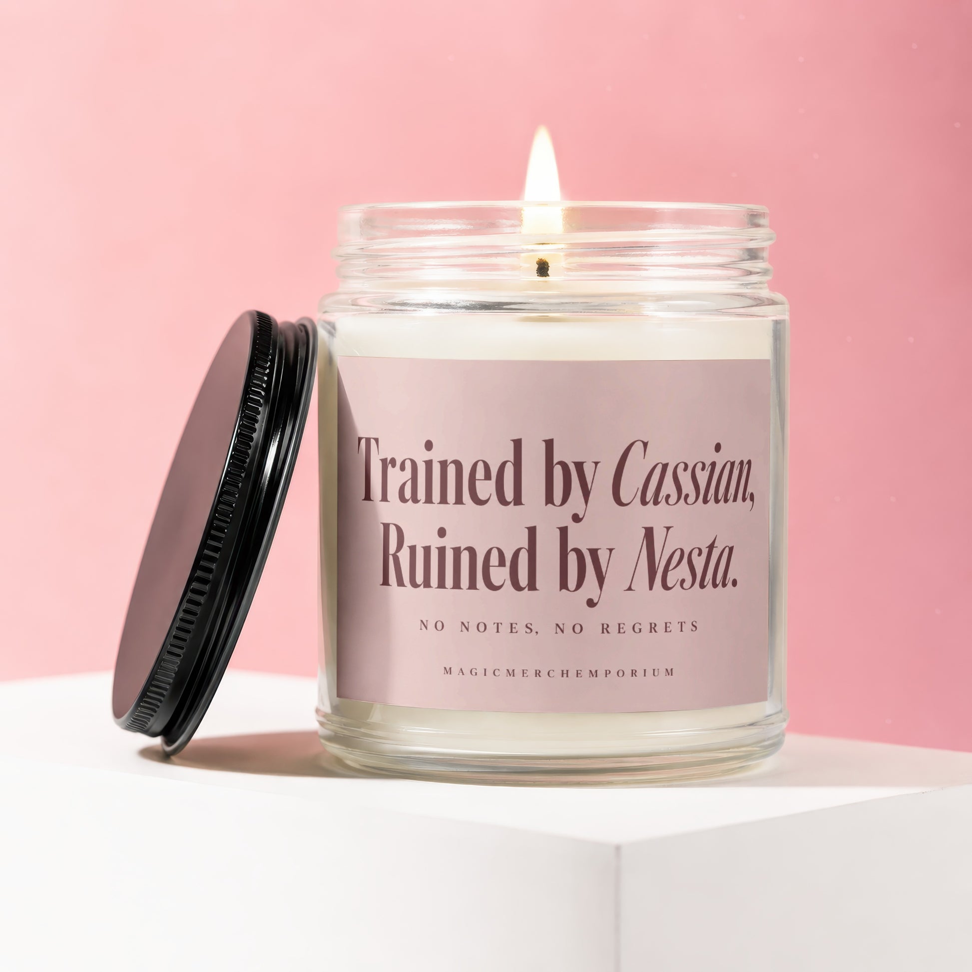 Candle with pink label that reads "Trained by Cassian, Ruined by Nesta."