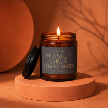 Amber jar candle labeled "Morally Grey Sympathizer" burning on an orange pedestal.