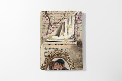 Blanket with vintage collage: cherry blossoms, sheet music, stars, and an oval portrait of a kissing couple.