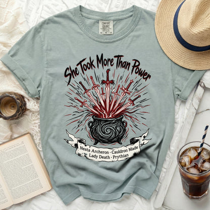 T-shirt with "She Took More Than Power" and swords in cauldron graphic.